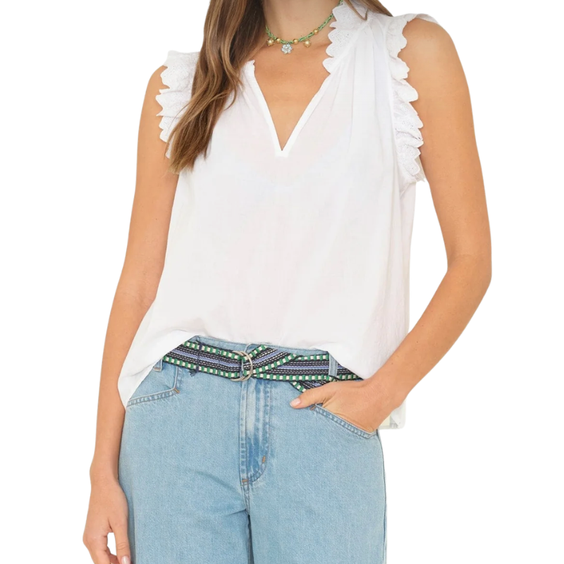 Woman wearing a white sleeveless top and blue jeans with a patterned belt on a white background