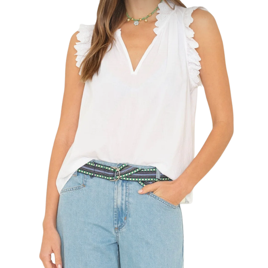 Woman wearing a white sleeveless top and blue jeans with a patterned belt on a white background