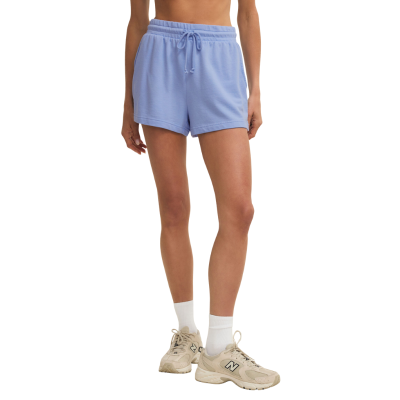 Person wearing light blue shorts and beige sneakers on a white background