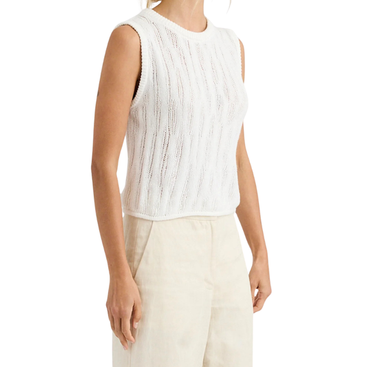Person wearing a white sleeveless top and beige pants on a white background