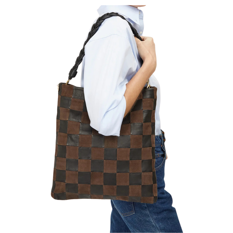 Person holding a brown woven handbag against a white background