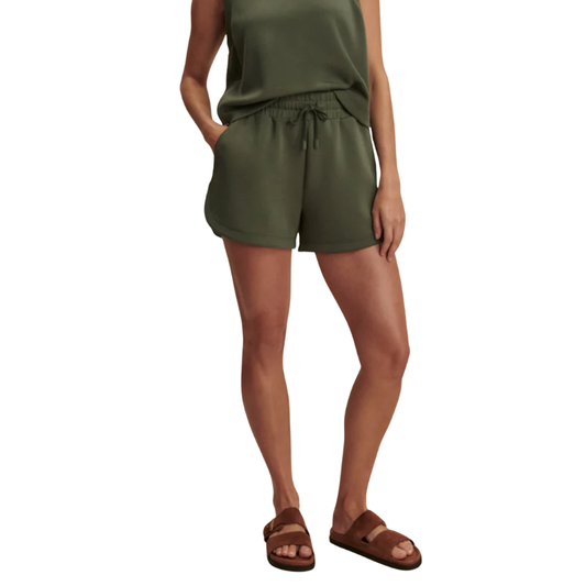 Person wearing green shorts and a sleeveless top on a white background