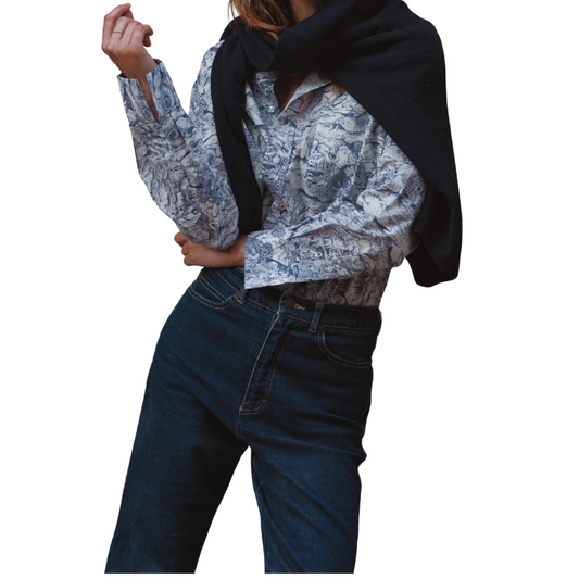 Person wearing a patterned shirt, dark scarf, and blue jeans on a white background