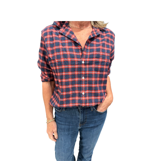 Person wearing a red and blue plaid shirt with rolled-up sleeves on a white background