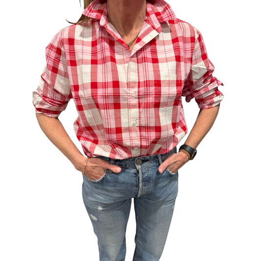 Person wearing a red and white plaid shirt with rolled-up sleeves and blue jeans on a white background