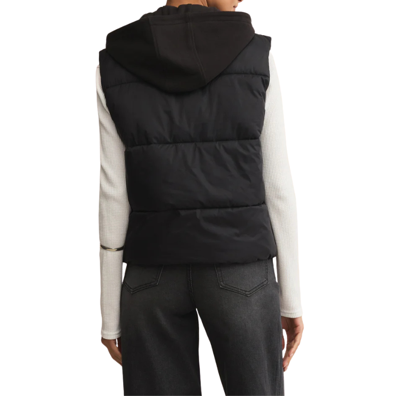 Person wearing a black puffer vest over a white long-sleeve shirt on a white background