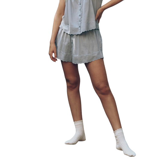 Person wearing a light-colored outfit with a skirt and white socks on a plain background