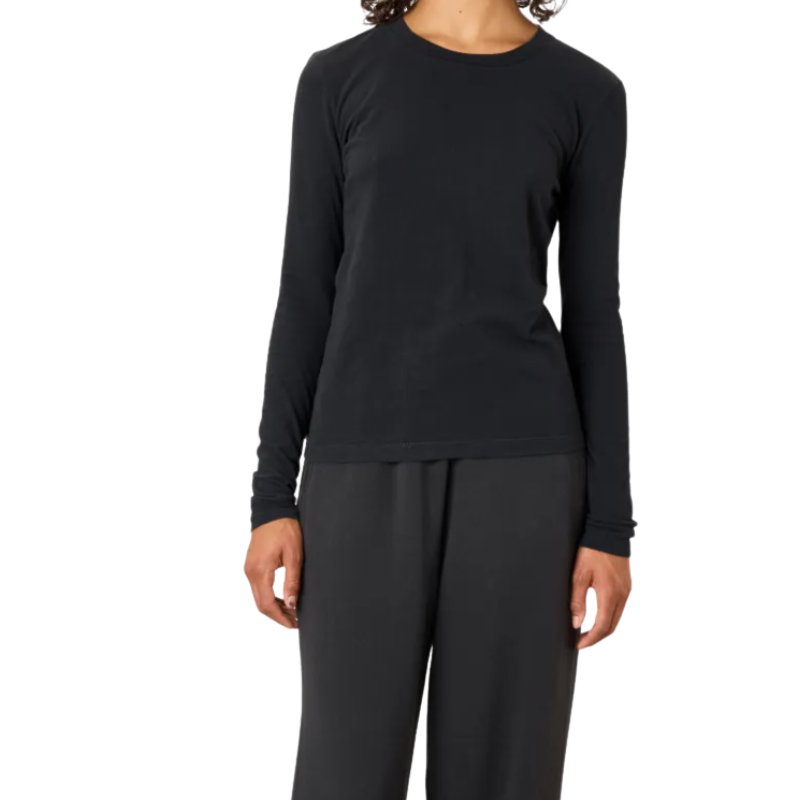A model wearing a black long-sleeve crewneck top and dark gray pants, shown from the neck down against a plain white background.