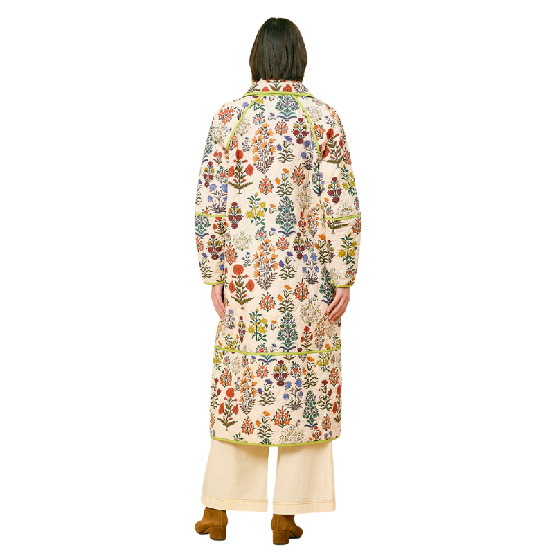Person wearing a long floral coat on a white background