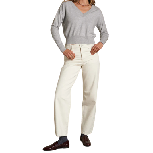 Person wearing a gray sweater and white pants on a white background