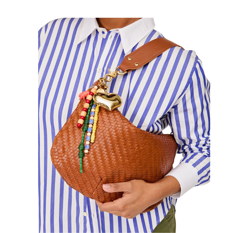 Person holding a brown woven handbag with decorative elements against a white background