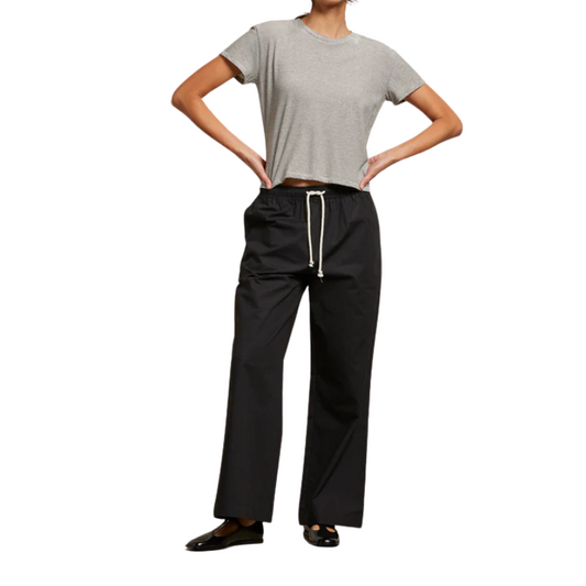 Person wearing a gray t-shirt and black pants with a white background