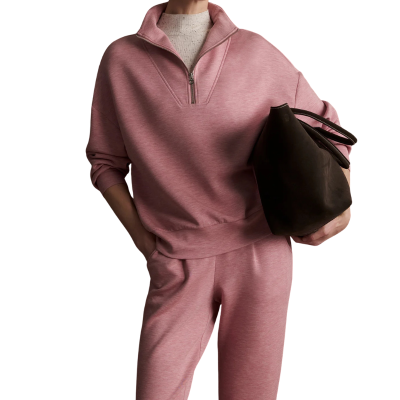 Person wearing a pink tracksuit holding a black bag on a white background