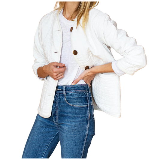 Person wearing a white jacket with brown buttons and blue jeans on a white background