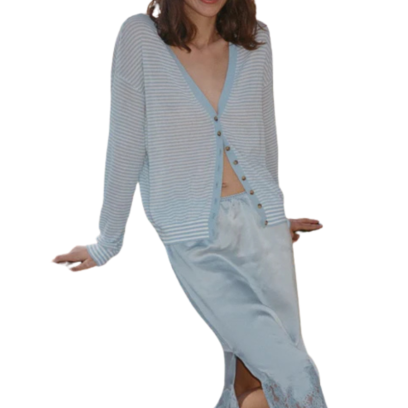 Woman wearing a light blue striped cardigan over a matching skirt on a white background