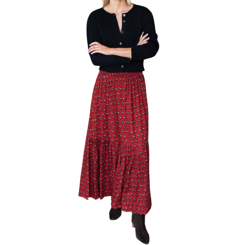 Person wearing a black cardigan and red patterned skirt on a white background