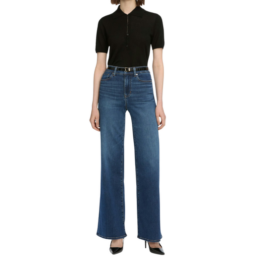 Person wearing a black polo shirt and blue jeans on a white background