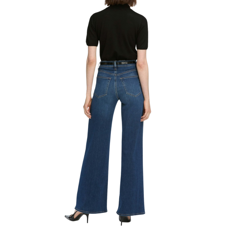 Person wearing blue jeans and a black top on a white background