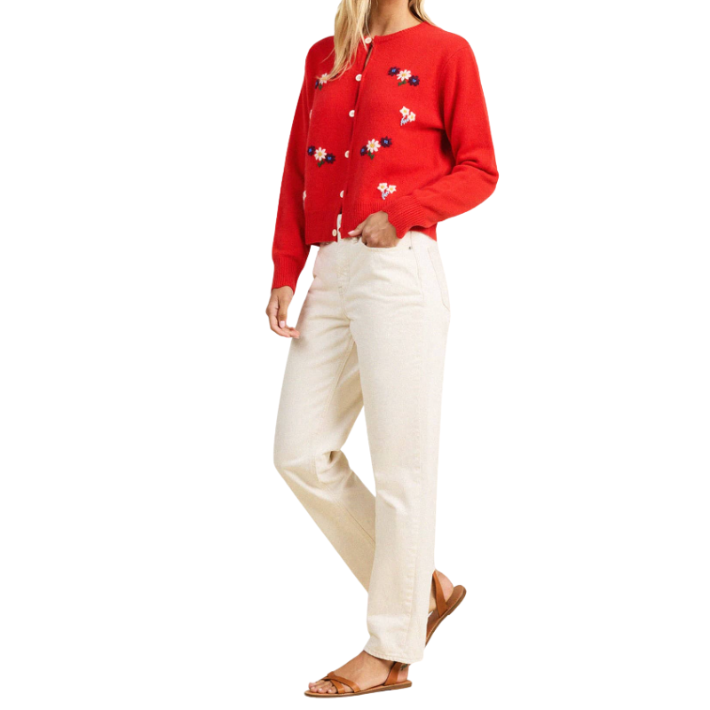 Person wearing a red embroidered shirt and white pants on a white background