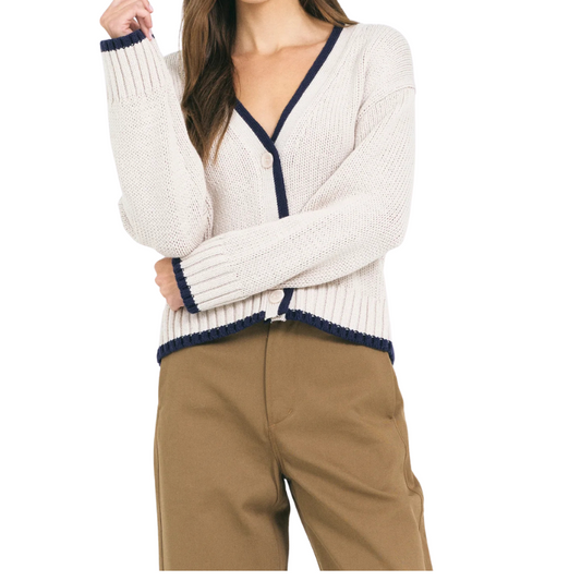 White cardigan with navy trim worn by a person on a white background