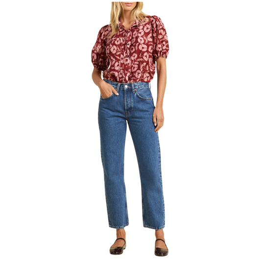 Woman wearing a red floral blouse and blue jeans on a white background