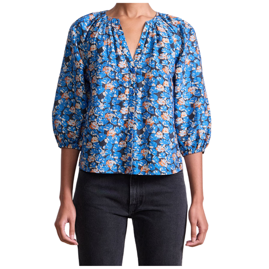 Blue floral blouse worn by a person on a white background
