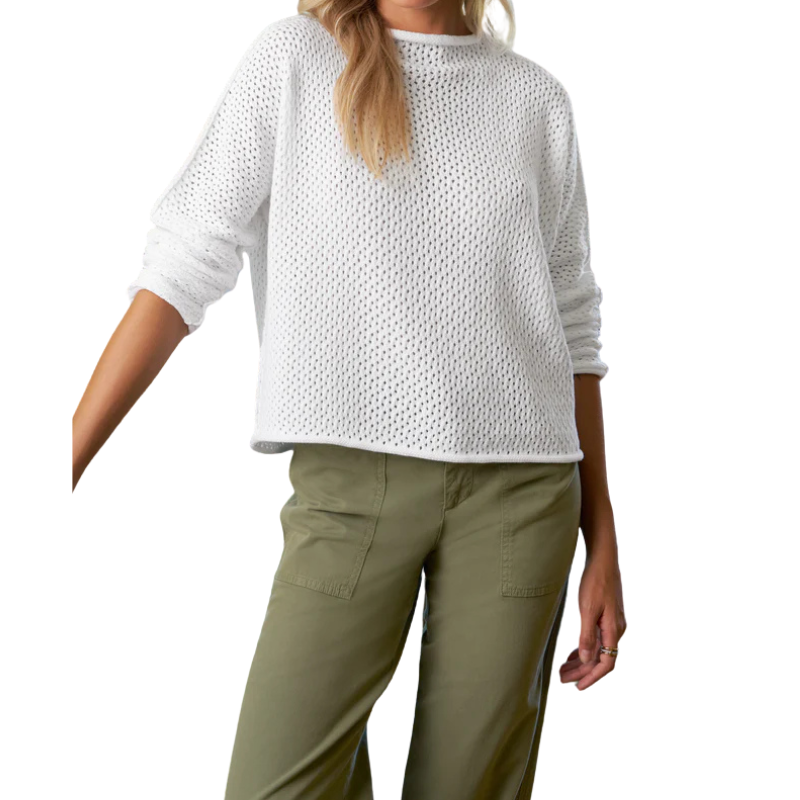 Woman wearing a white textured sweater and green pants on a white background