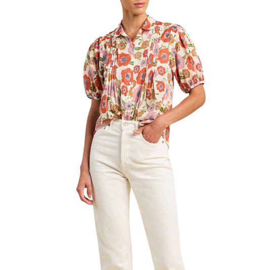 Person wearing a floral blouse and white pants on a white background
