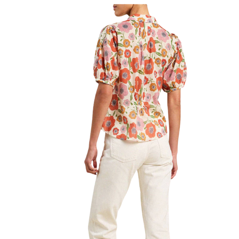 Person wearing a floral blouse and white pants on a white background