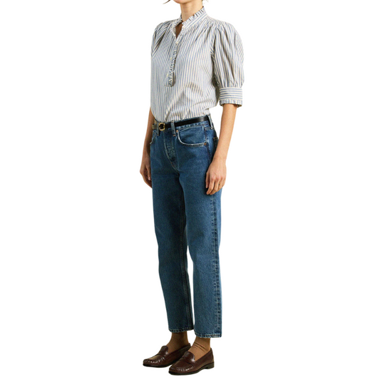 Person wearing a striped shirt and blue jeans on a white background