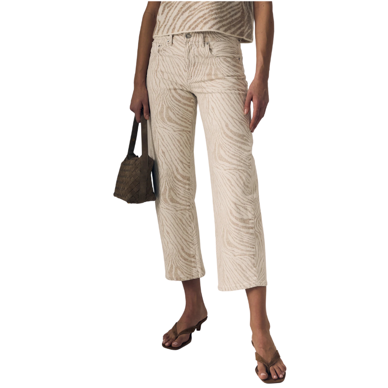 Woman wearing beige striped pants holding a textured handbag on a white background