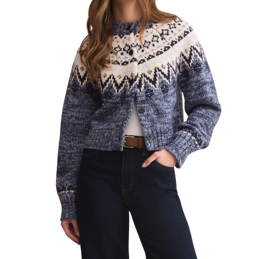 Person wearing a patterned sweater and dark jeans on a white background