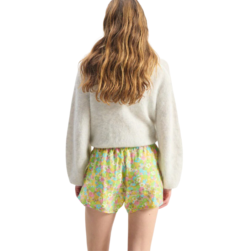 Person wearing a white sweater and colorful shorts on a white background