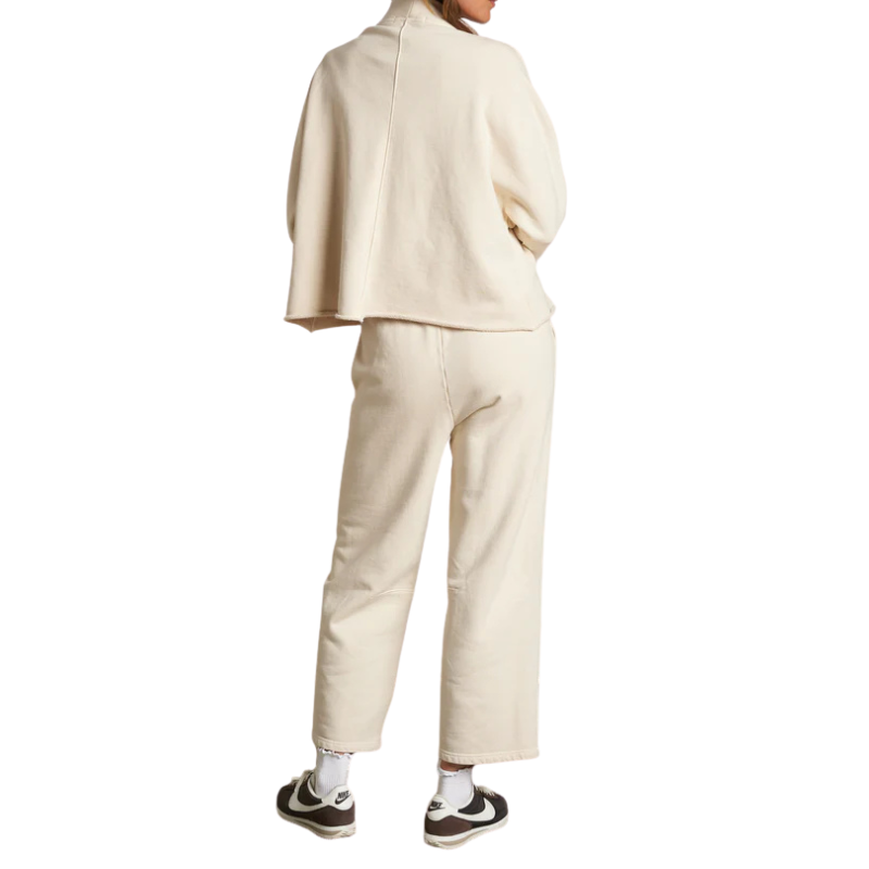 Person wearing a beige outfit with a jacket and pants on a white background