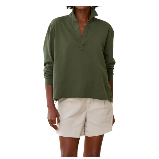 Person wearing a green long-sleeve shirt and beige shorts on a white background