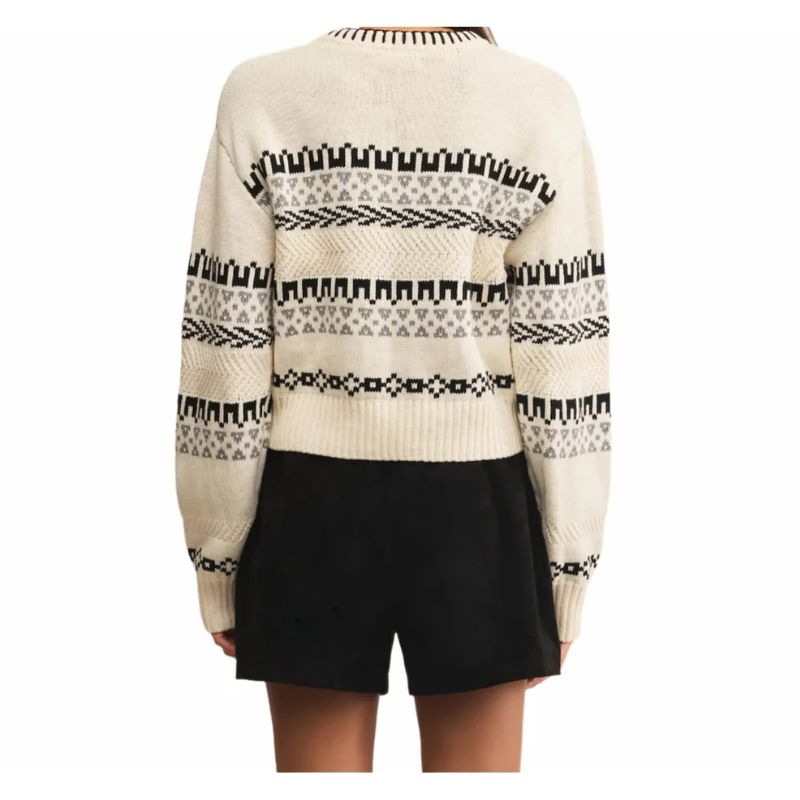 Beige sweater with black pattern worn by a person on a white background