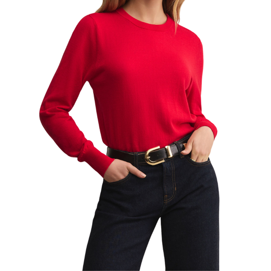 Person wearing a red sweater and black jeans on a white background