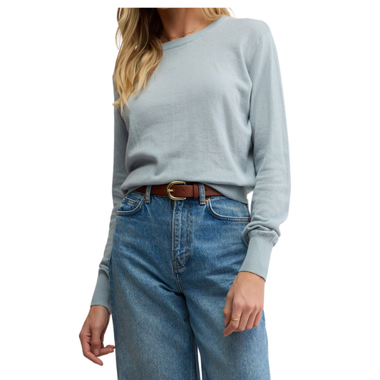 Person wearing a light blue sweater and blue jeans on a white background
