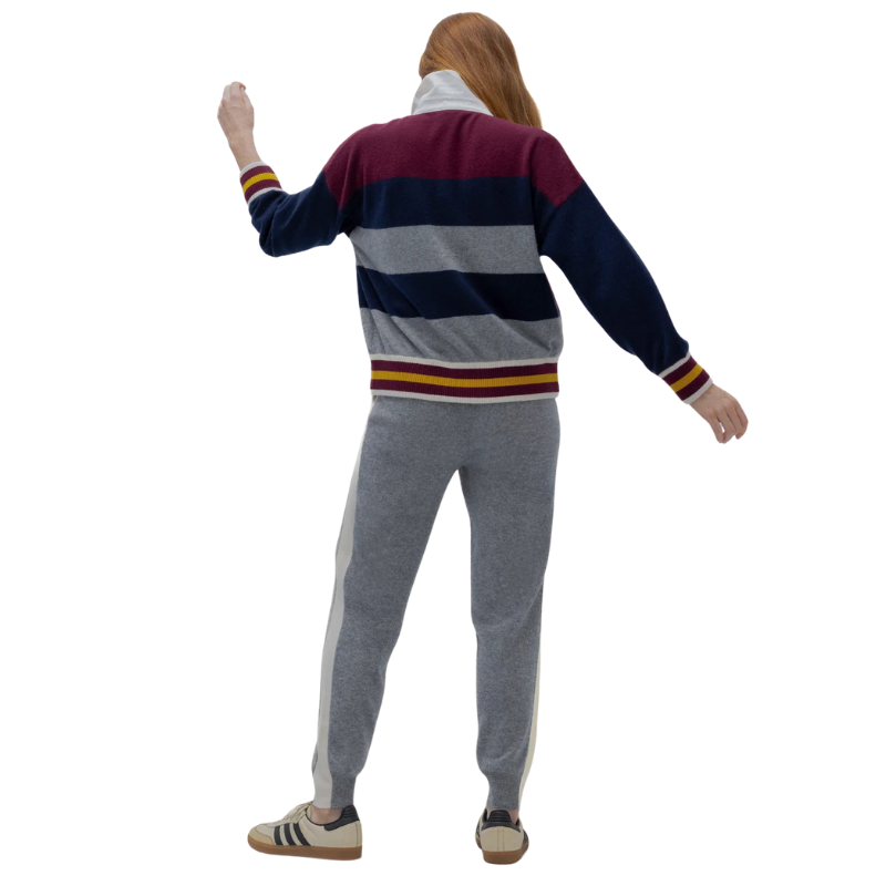 Person wearing a striped sweater and gray pants on a white background