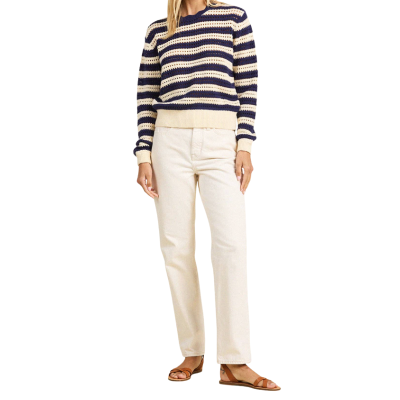 Person wearing a striped sweater and white pants on a white background