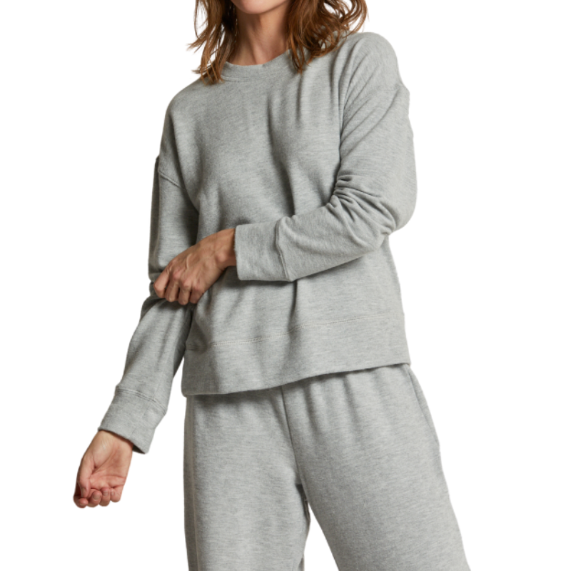 Person wearing a gray sweatshirt and pants on a white background