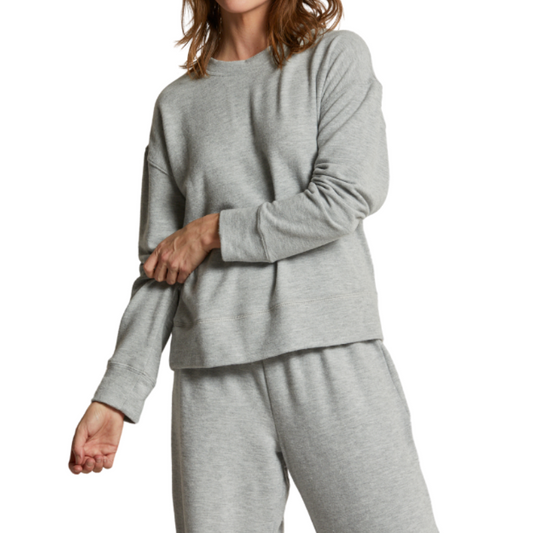 Person wearing a gray sweatshirt and pants on a white background