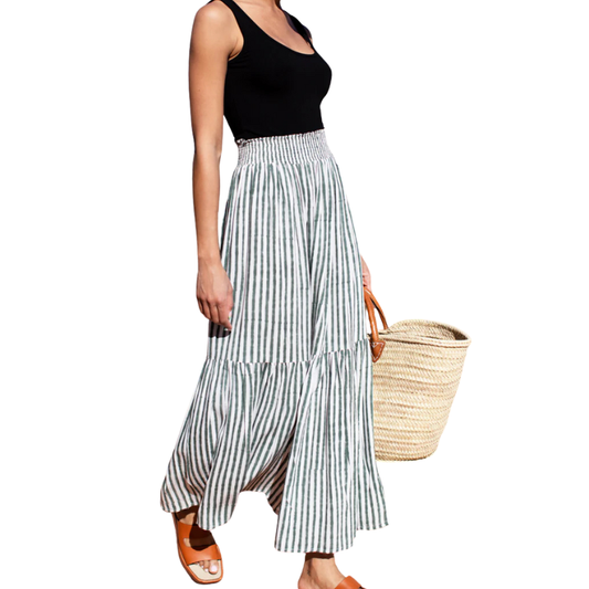 Woman wearing a black top and striped skirt holding a straw bag on a white background