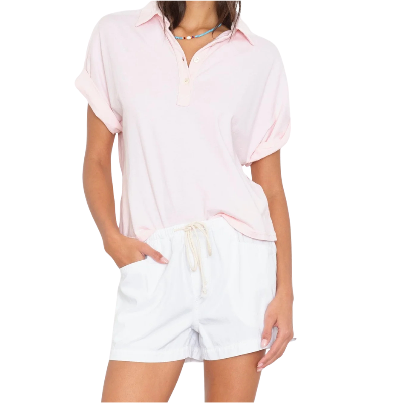 Person wearing a light pink shirt and white shorts on a white background