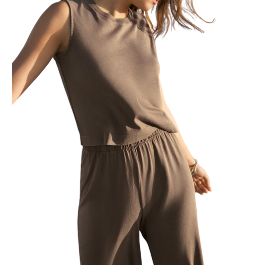 Person wearing a brown sleeveless top and pants on a white background