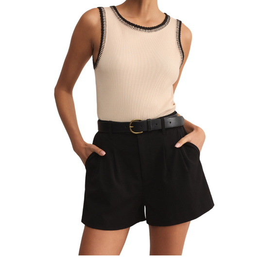 Person wearing a beige sleeveless top with black trim and black shorts on a white background