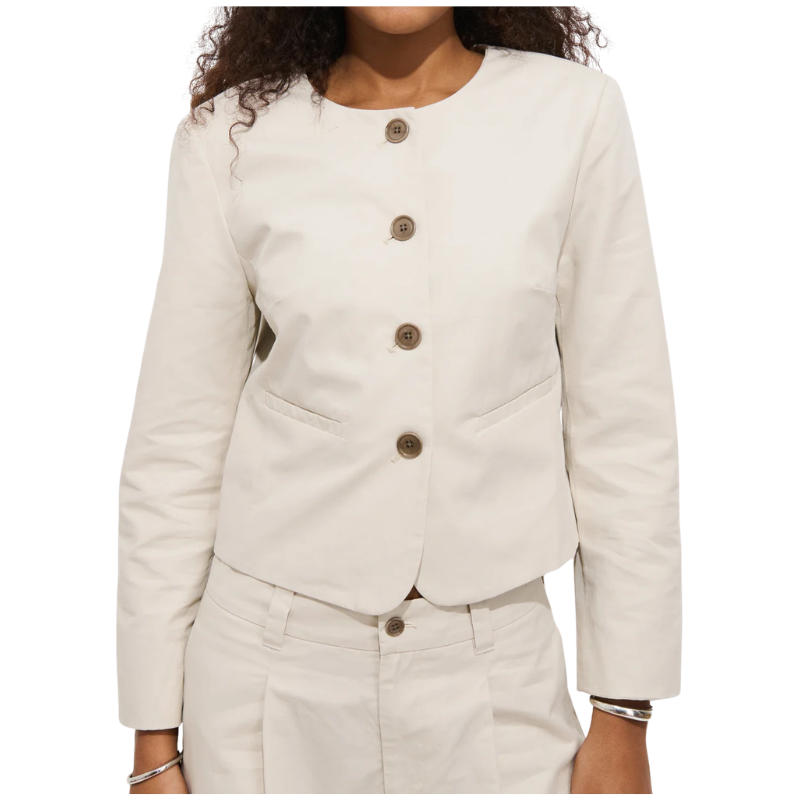 White blazer with brown buttons worn by a person on a white background