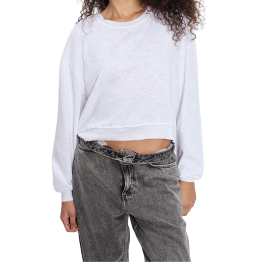 Person wearing a white cropped sweatshirt and gray jeans on a white background
