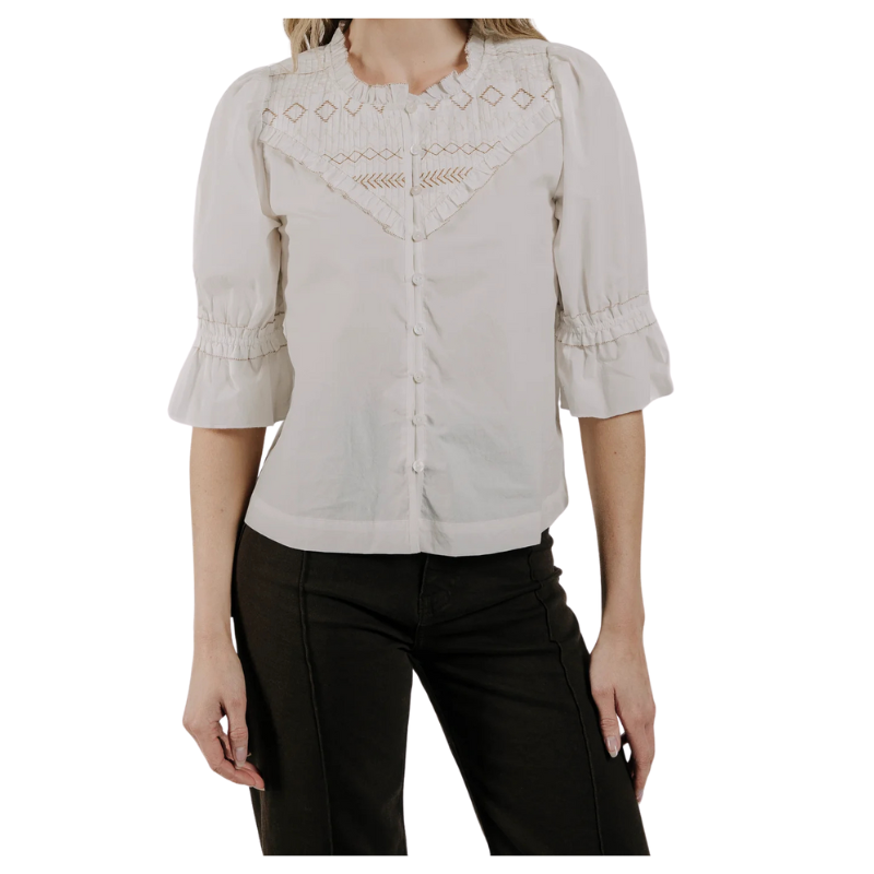 Woman wearing a beige blouse with intricate patterns on a white background