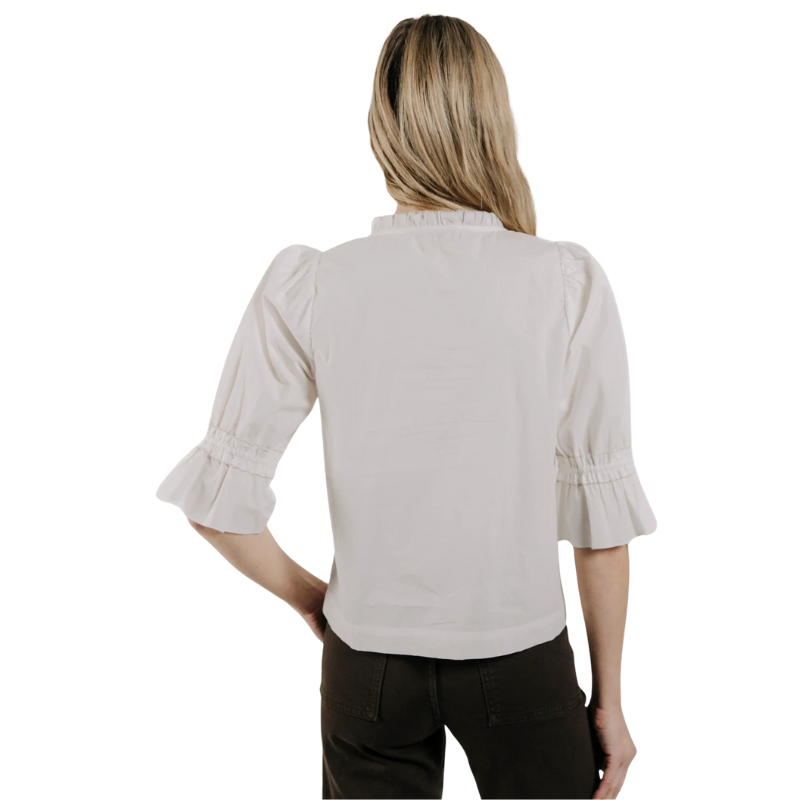 Woman wearing a light gray blouse with ruffled sleeves on a white background